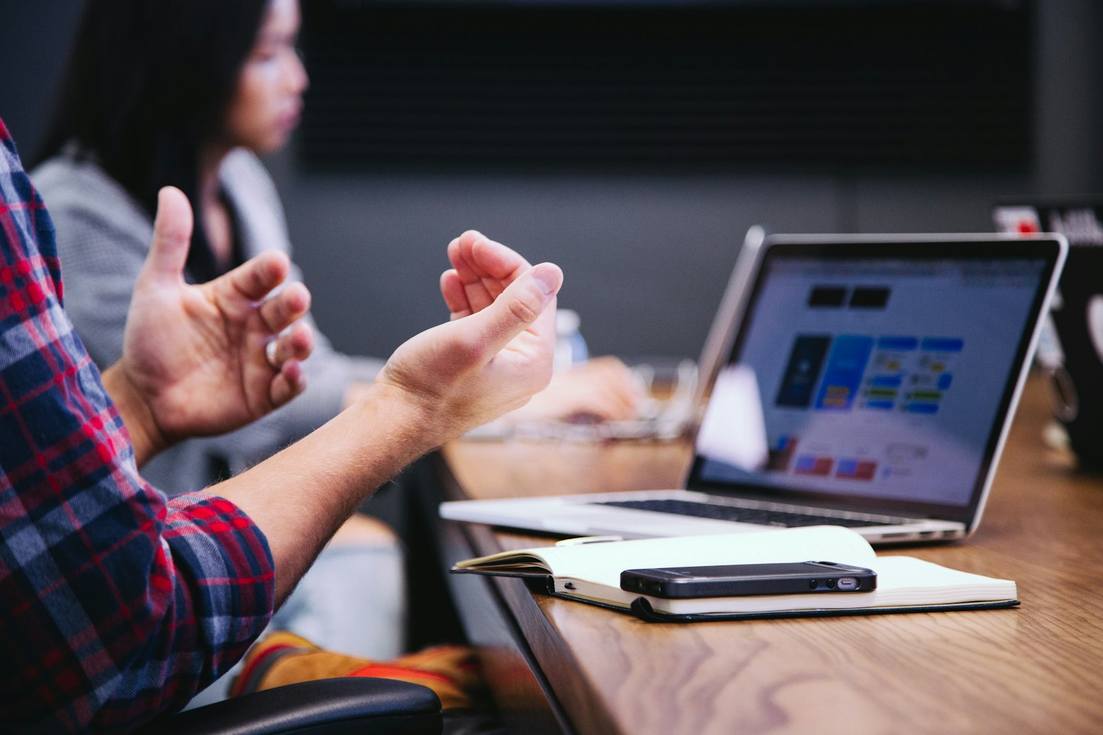 A person gesturing during a meeting with a laptop